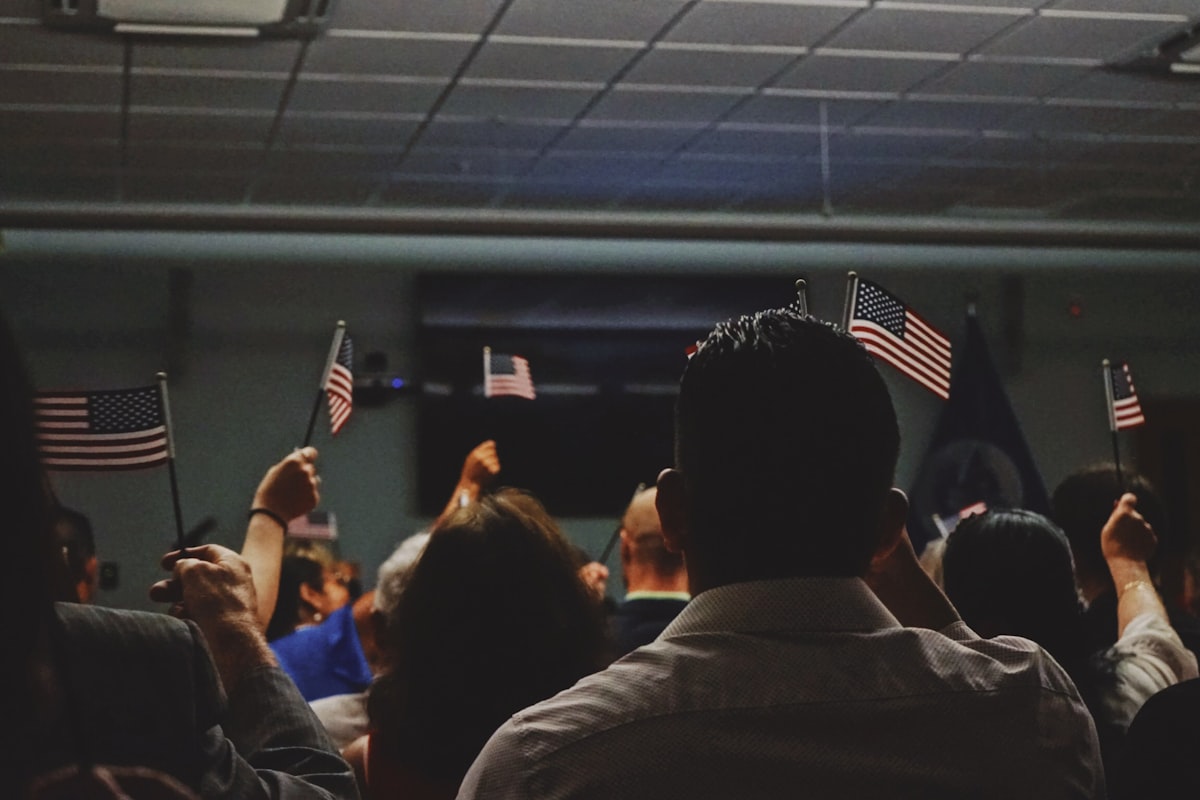 New citizens at a U.S. naturalization ceremony raising small handheld American flags